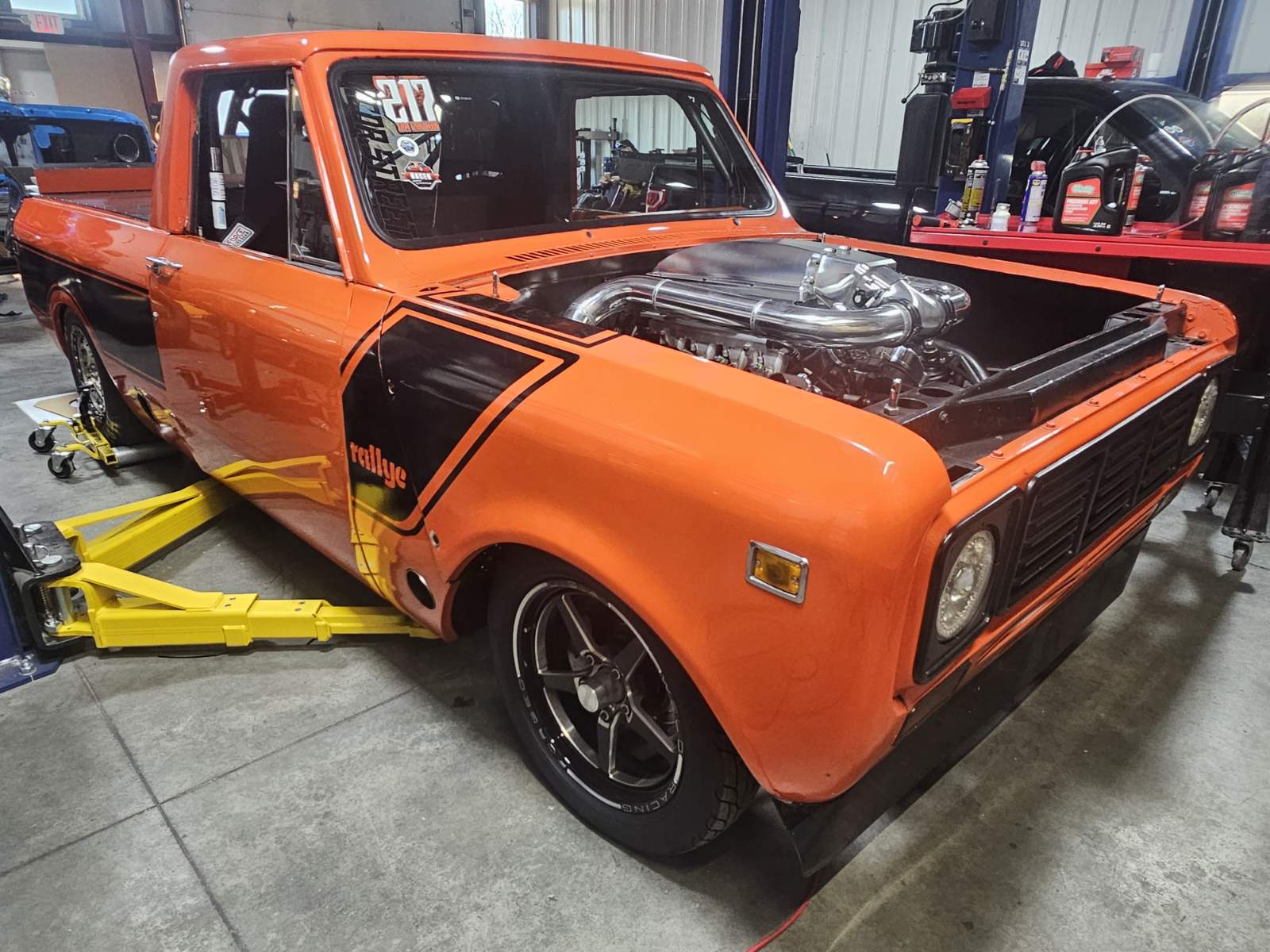 1976 Scout truck side view on lift - orange with black accents and massive stance